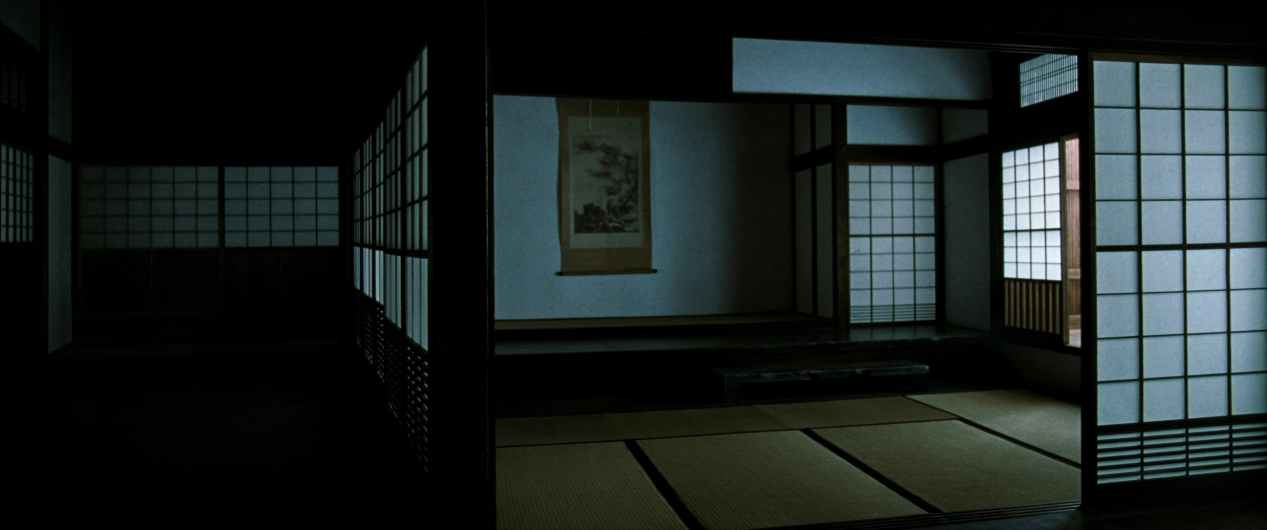 An empty tatami room with shoji screens and a single scroll in the alcove